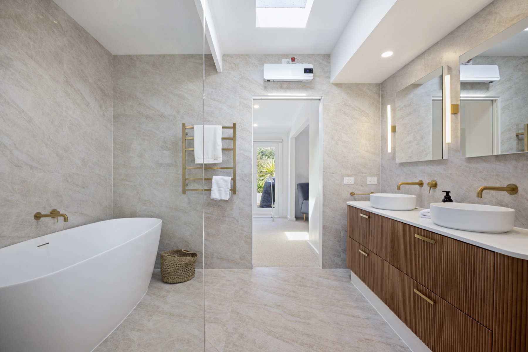 Freestanding bath with stone-look tiles and brushed brass fittings