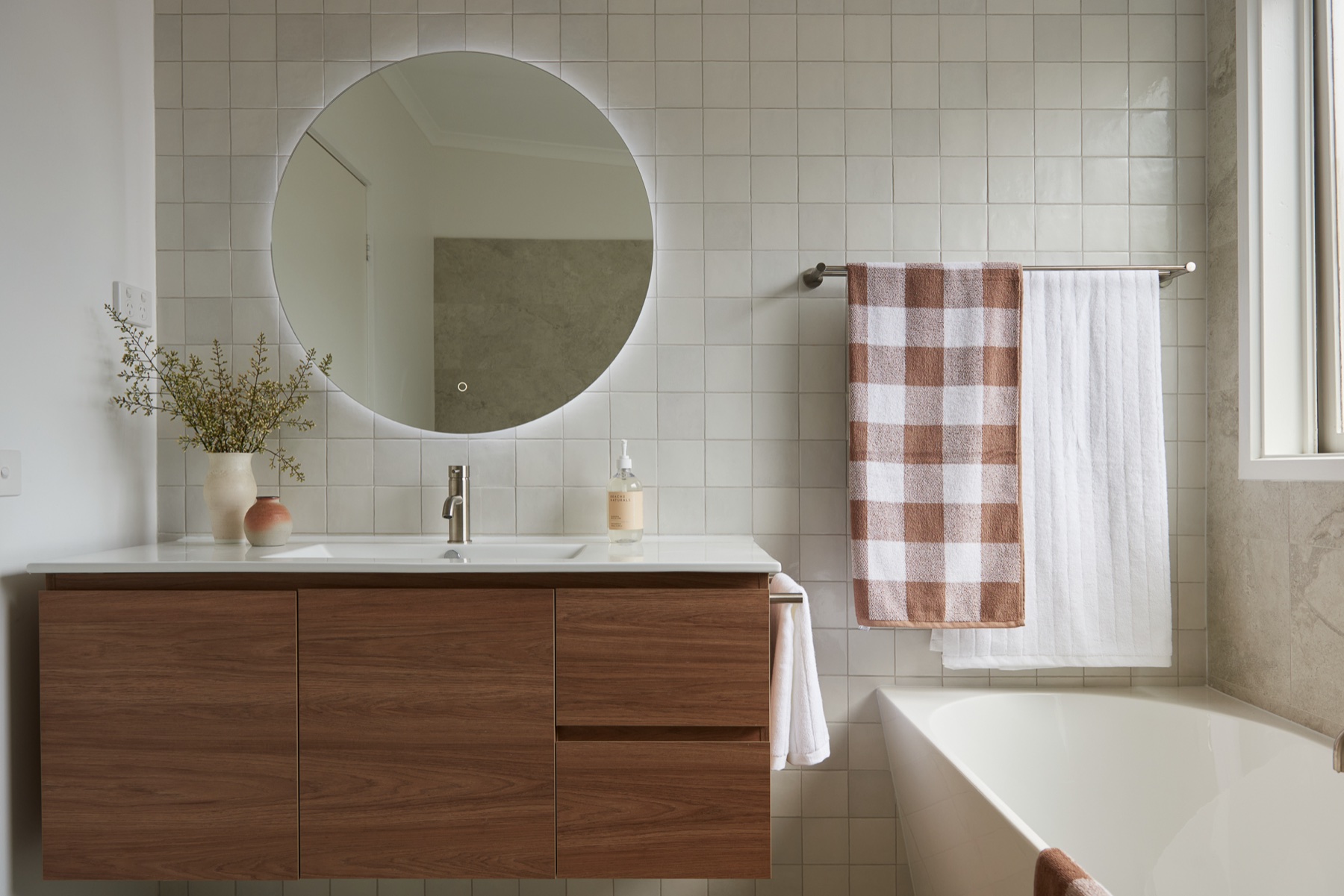 Bathroom with timber vanity, round mirror and built-in bath